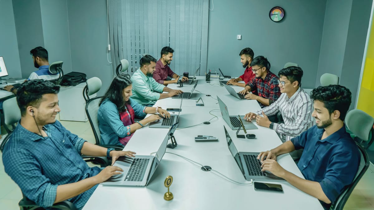 The Ecommerce Pune team at work in the Shaniwar Peth office: nine people along a long white desk, each on a laptop.